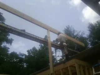 Carpenter setting a ridge beam over a new addition frame — Ice Dam Removal by Roofing Brothers in Merlin
