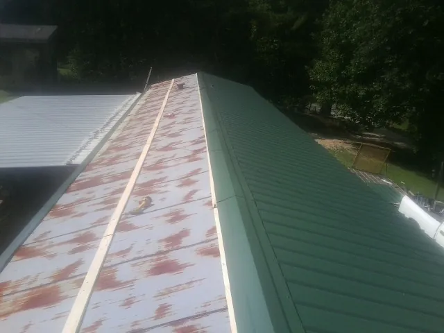 Old rusted panels beside newly installed green metal roofing — Wind Damage Roof Repair by Roofing Brothers in Merlin