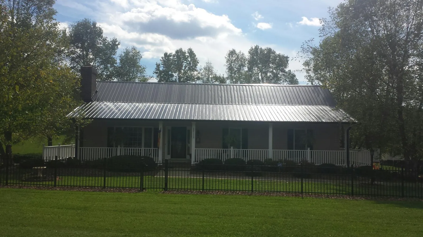 Gray metal roof on a brick ranch with a full width front porch — Gutter Guard Installation work by our crew in Merlin